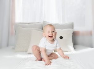 uśmiechnięte niemowlę w białych ubrankach